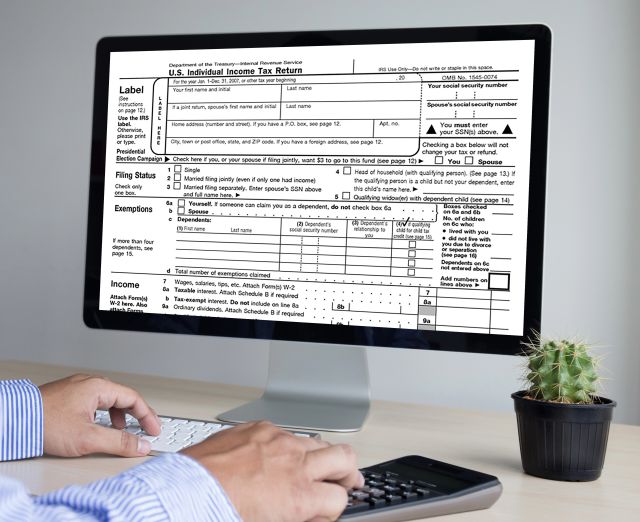 man filling out tax form on computer